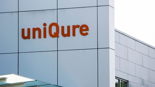 The uniQure company name in large orange letters on the exterior cladding of a modern office building